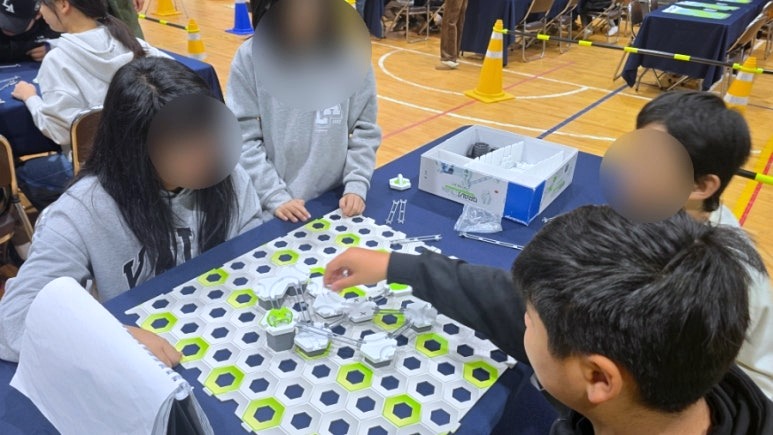 학생들이 그래비트랙스 트랙 조각을 놓고 경로를 조정하는 장면